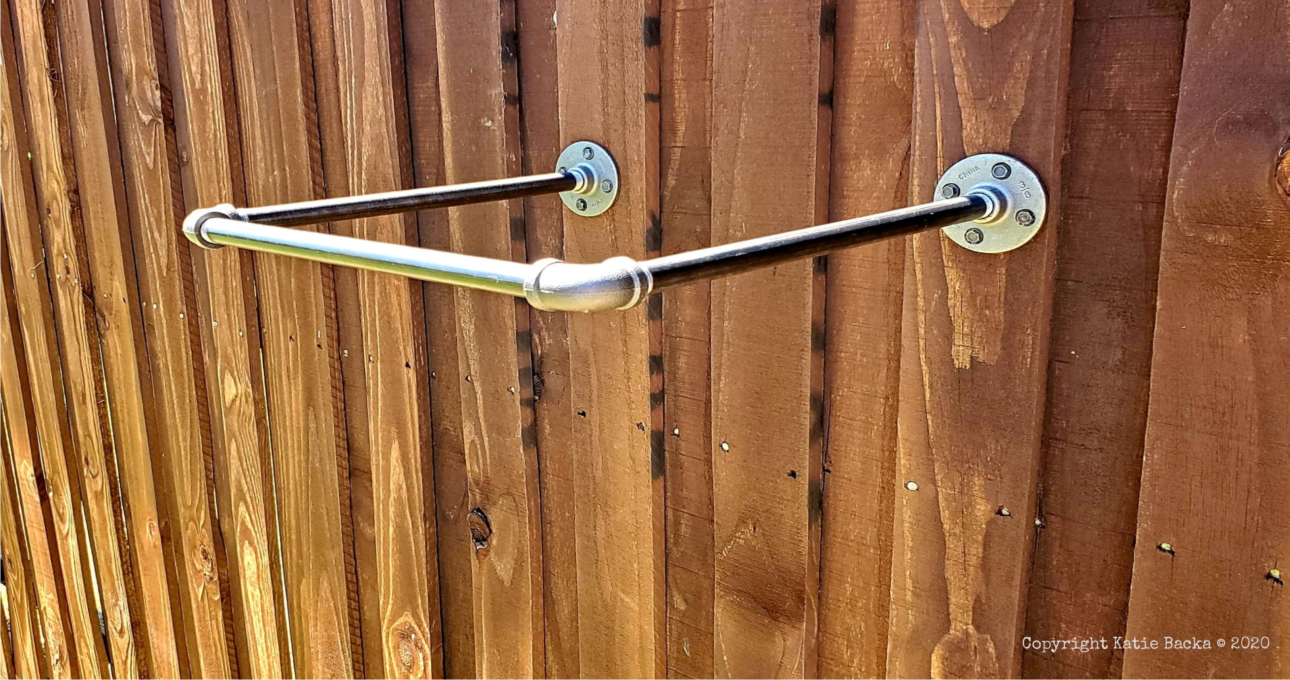 Iron pipe shelf attached to a fence