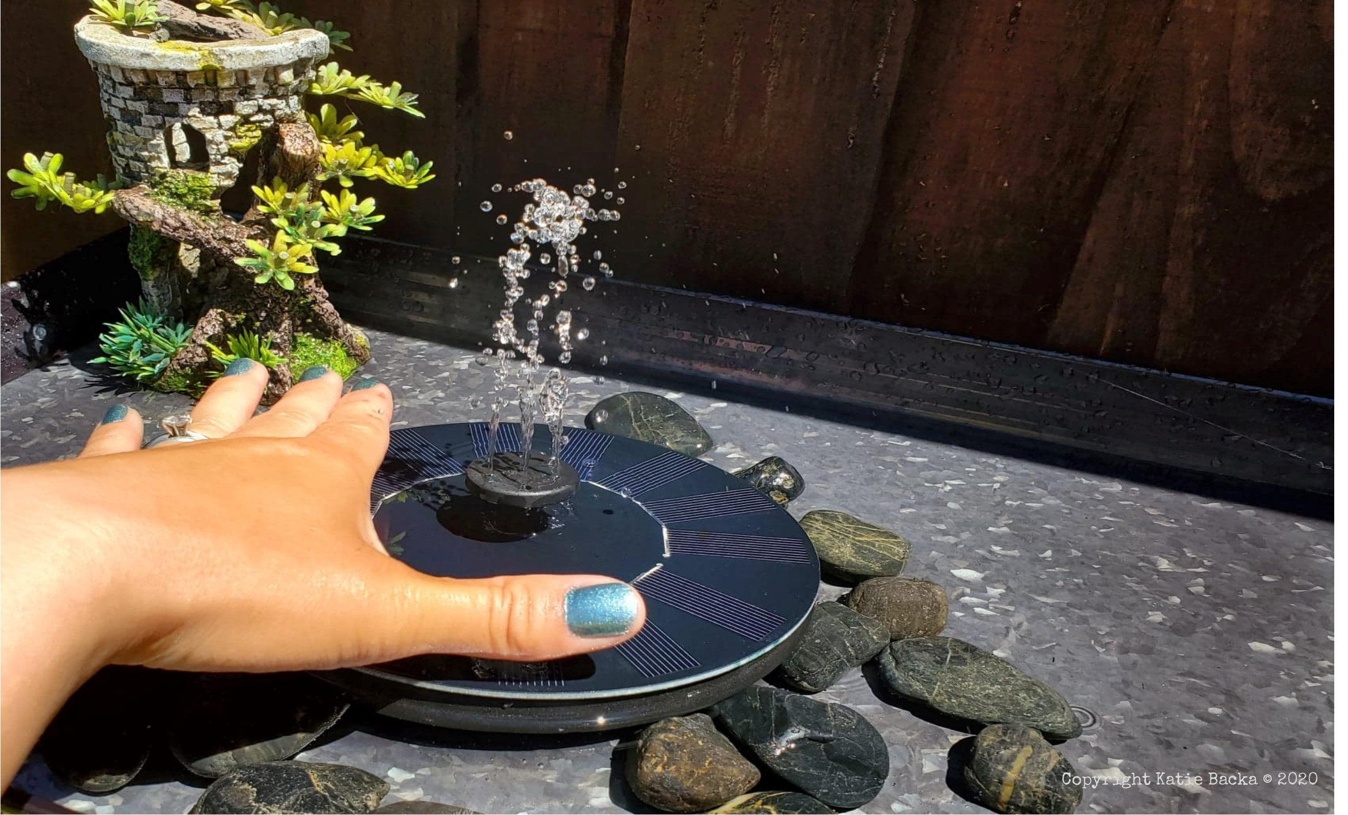 Decorated bird bath with my hand in the picture for scale